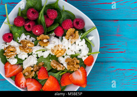 Portrait de la salade de fruits avec des framboises, fraises, noix, fromage bleu Contre fond de bois Banque D'Images