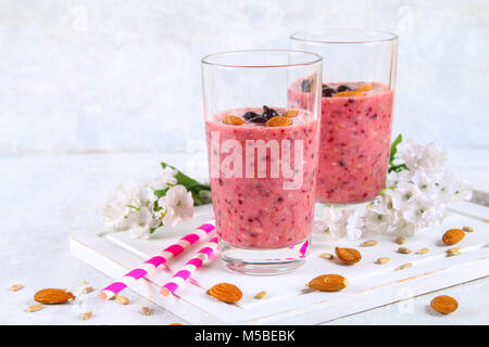 Des smoothies de fruits des bleuets, bananes et amandes dans des verres à cocktail avec tubes sur une planche de bois blanc Banque D'Images