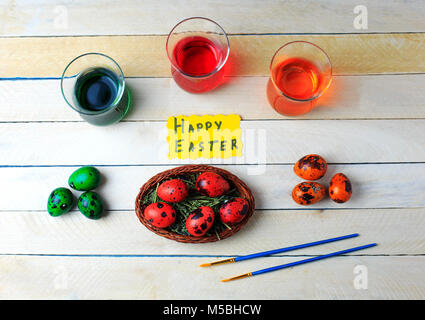 Des oeufs de cailles dans le processus de dessin avec peinture alimentaire colorés rouge, vert et orange. Concept de Pâques. Vue d'en haut. Joyeuses Pâques. Banque D'Images