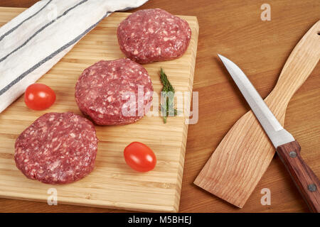 Escalope de viande hachée crue sur une planche à découper en bois. Banque D'Images