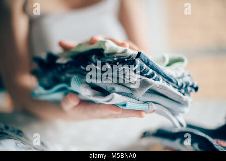 Tri des vêtements de bébé nouveau-né de la mère pour le repassage à domicile dans le cadre des activités quotidiennes dans les services de garde, selective focus Banque D'Images