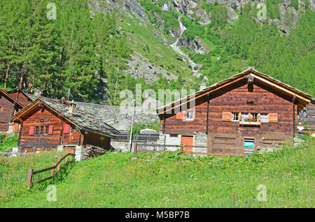 Alpine chalets dans leurs prés remplis de fleurs avec un ruisseau et montagne en arrière-plan Banque D'Images