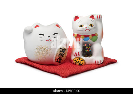 Le japonais maneki neko, le chat de la chance sur un oreiller rouge isolé sur fond blanc Banque D'Images