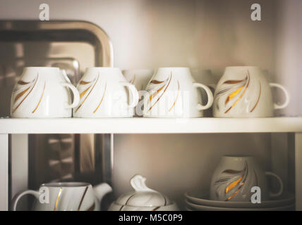 Libre de tasses à café décorées de blanc dans un placard Banque D'Images