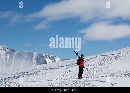 Avec skieur skis sur l'épaule aller jusqu'en haut de la montagne dans jolie journée soleil. Montagnes du Caucase en hiver, la Géorgie, la région, le Mont Gudauri. Kudebi Banque D'Images