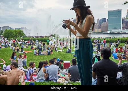 Jeune femme à la recherche de son appareil photo à Marcy's 4 juillet d'artifice sur l'East River à New York City Banque D'Images