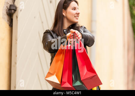 Jolie femme montre son shopping cadeaux sacs avec des vêtements et des bijoux qu'elle a achetées sur un jour de la vente Banque D'Images