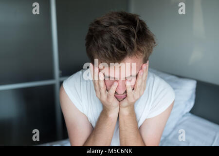 L'homme déprimé assis dans son lit et se sentir mal Banque D'Images