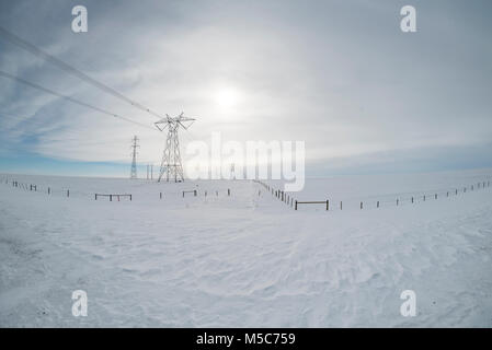 L'Alberta, Canada. Pylônes électriques/tours de transmission dans les Prairies en hiver, perspective fisheye. Banque D'Images