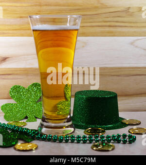 St Patricks Day café traditionnel en verre rempli de bière, petit morceau de mousse, chapeau vert, gree trèfle, perles vert et les pièces d'or. Banque D'Images