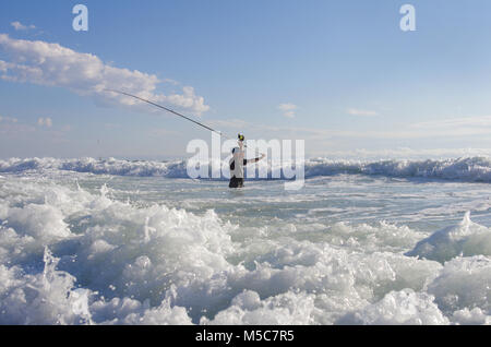 Pêcheur de surf dans les vagues. Scène de pêche. surf casting. Banque D'Images