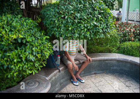 19.02.2018, Singapour, République de Singapour, en Asie - Un homme est assis sous un arbre dans le jardin public de la People's Park Complex dans Chinatown. Banque D'Images