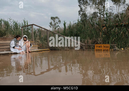 Pèlerins chrétiens assis sur la rive de la Qaser el Yahud site baptismal Kasser aussi Qasser Yehud al ou le nom officiel de la partie occidentale de l'emplacement traditionnel du baptême de Jésus par Jean le Baptiste dans le Jourdain région Vallée de la Cisjordanie Israël Banque D'Images