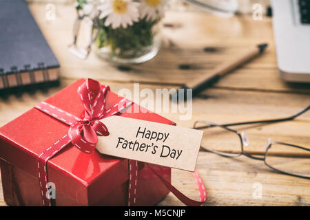 Concept de la fête des pères. Boîte cadeau rouge avec ruban rouge et happy fathers' Day tag, le flou d'arrière-plan de bureau Banque D'Images