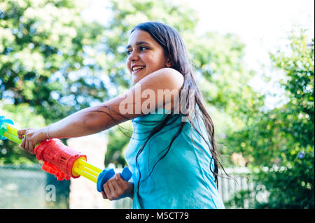 Les enfants jouent dans le jardin avec des fusils et carabines de l'eau sur une journée ensoleillée ayant beaucoup de plaisir Banque D'Images