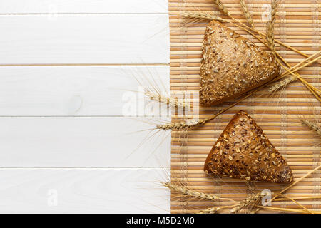 Plusieurs petits grains pain multi forme triangulaire ensemble saupoudré de graines de tournesol, de lin et de graines de sésame et le blé et l'orge des pics. Banque D'Images