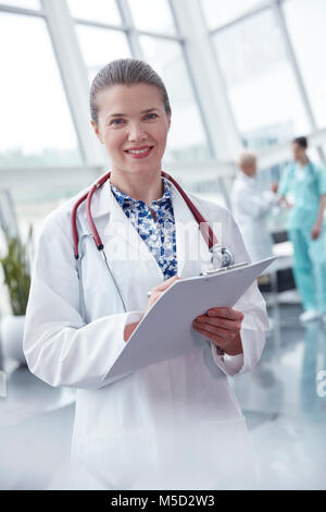 Portrait souriant, confiant female doctor with clipboard in hospital Banque D'Images