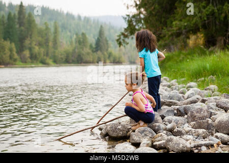 Soeurs fille jouant avec des bâtons à Lakeside Banque D'Images