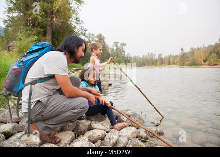 Père et filles avec des bâtons de pêche à Lakeside Banque D'Images