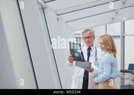 Médecin homme montrant x-ray à female patient in hospital Banque D'Images