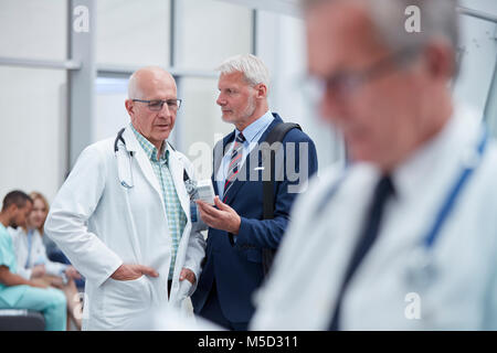 Représentant pharmaceutique mâle montrant médicament sur doctor in hospital Banque D'Images