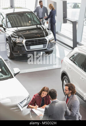 Les vendeurs de voitures et les clients de car dealership showroom Banque D'Images