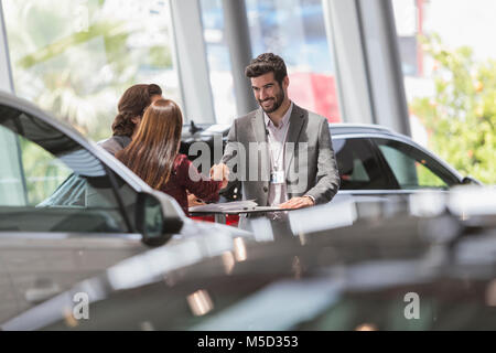 Vendeur de voiture de liaison avec les clients de car dealership showroom Banque D'Images
