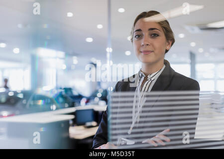 Portrait confiant car saleswoman in car dealership showroom Banque D'Images