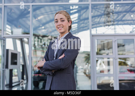 Confiant, Portrait smiling saleswoman standing voiture à l'extérieur du car dealership showroom Banque D'Images