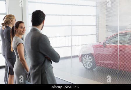 Vente de voiture à la recherche de nouvelles personnes, en voiture rouge car dealership showroom Banque D'Images