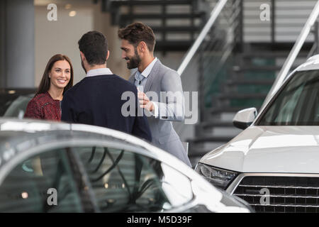 Parler aux vendeurs de voiture female customer in car dealership showroom Banque D'Images