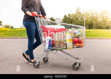 Méconnaissable jeune fille se tient à côté d'un panier plein de produits alimentaires Banque D'Images