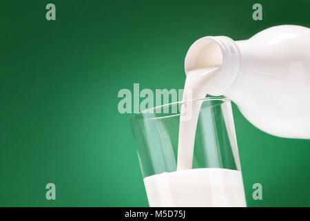 Le kéfir verser une bouteille de blanc dans un verre sur un fond vert Banque D'Images