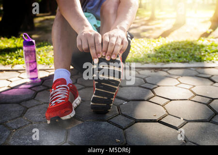 Les athlètes sont d'Asie s'étend ses jambes avant l'exécution de travaux à des route en parc. Courir pour perdre du poids et une bonne santé Banque D'Images