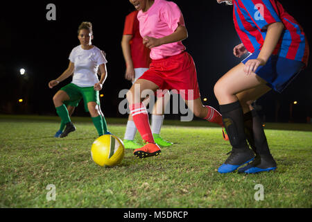 Les jeunes joueuses de soccer sur le terrain de jeu de nuit, courir pour ball Banque D'Images