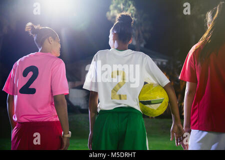 Les jeunes joueuses de soccer avec ball parler sur terrain de nuit Banque D'Images