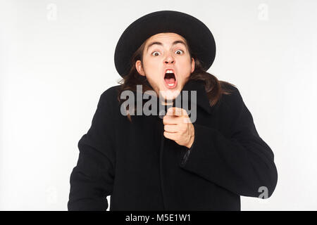 L'homme en manteau et chapeau, bouche ouverte, montrer du doigt la caméra. Studio shot, isolé sur fond blanc Banque D'Images