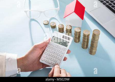 Close-up of a Businesswoman Calcul Finances à l'aide de pièces avec calculatrice graphique sur 24 Banque D'Images