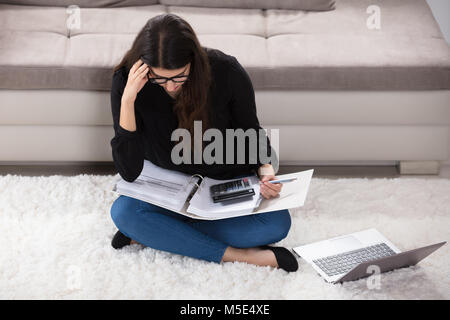 Jeune femme envisage des projets de calcul à la maison Banque D'Images