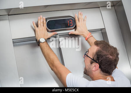 L'homme a peur de numéro treize sur l'affichage de l'élévateur. Banque D'Images