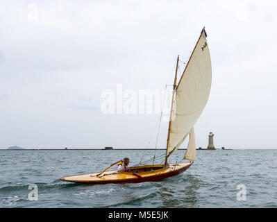 Une petite gaff rigged yacht en bois passé voiles de brise-lames du Plymouth sur l'image. Banque D'Images