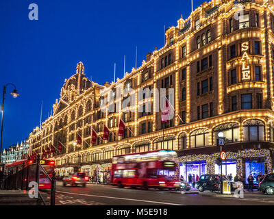 Harrods soldes feux le crépuscule grand magasin éclairé la nuit avec le panneau « Sale » fait des courses de bus rouges et passe des taxis sur la route ULEZ Knightsbridge Londres SW1 Banque D'Images