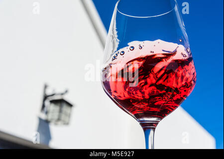 DÉGUSTATION DE VIN ROUGE EN PLEIN AIR BOIRE tourbillonnant et évaluation d'un verre de vin rouge clair fin en plein air dégustation de vin bleu ciel ensoleillé en extérieur situation extérieure Banque D'Images