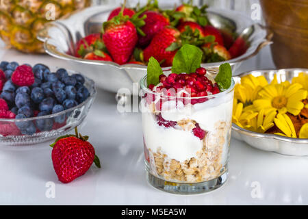 Petit-déjeuner frais avec du muesli, yaourt, fruits et fleurs comestibles Banque D'Images