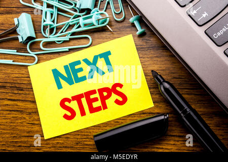 Texte d'annonce de l'écriture manuscrite indiquant les prochaines étapes. Concept d'affaires pour les futurs Golas et cible écrit sur papier sticky note suivante sur fond de bois Banque D'Images
