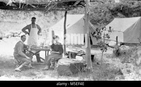 Grand Canyon - Historique Camp rouille rouille c Kolb tentes du camp. ELLSWORTH KOLB ASSIS AVEC UNE JEUNE FEMME À l'extérieur coin repas sous un toit de chaume. Impôts en tablier, debout. Vers 1907. KOLB BROS. Banque D'Images