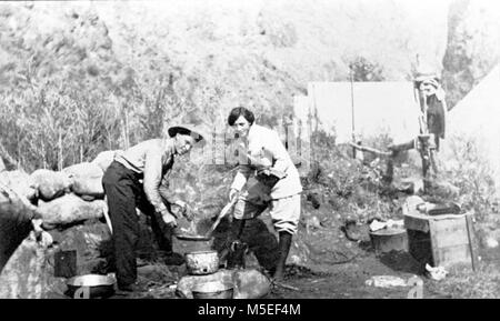 Grand Canyon - Historique Camp rouille rouille c Kolb CAMP. ELLSWORTH KOLB ET JEUNE FEMME AU-DESSUS D'UN FEU DE CUISSON. Les tentes du camp ET LES MURS DE CANYON derrière. Vers 1907 KOLB BROS. Banque D'Images