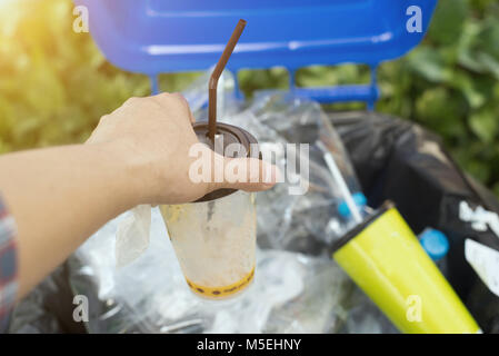 Vieil homme mains jetant verres en plastique vides dans le bac. Banque D'Images