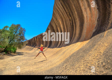 Australian Outback liberté concept. Happy woman jumping à Wave Rock en Hyden, ouest de l'Australie. Cavalier femelle dans une formation rocheuse naturelle de la forme d'une vague en Hyden Wildlife Park. Banque D'Images