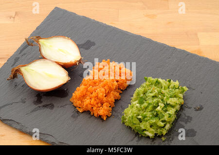 Mirepoix, légumes tricolore organisé sur l'ardoise plaque noire, concept pour la haute cuisine, à partir de ci-dessus, orange émincé carotte, céleri et oignon vert Banque D'Images